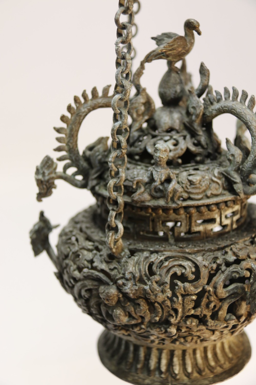 A dark patinated bronze hanging incense burner featuring dragon openwork motifs and a bird finial suspended by three link chains. View XI