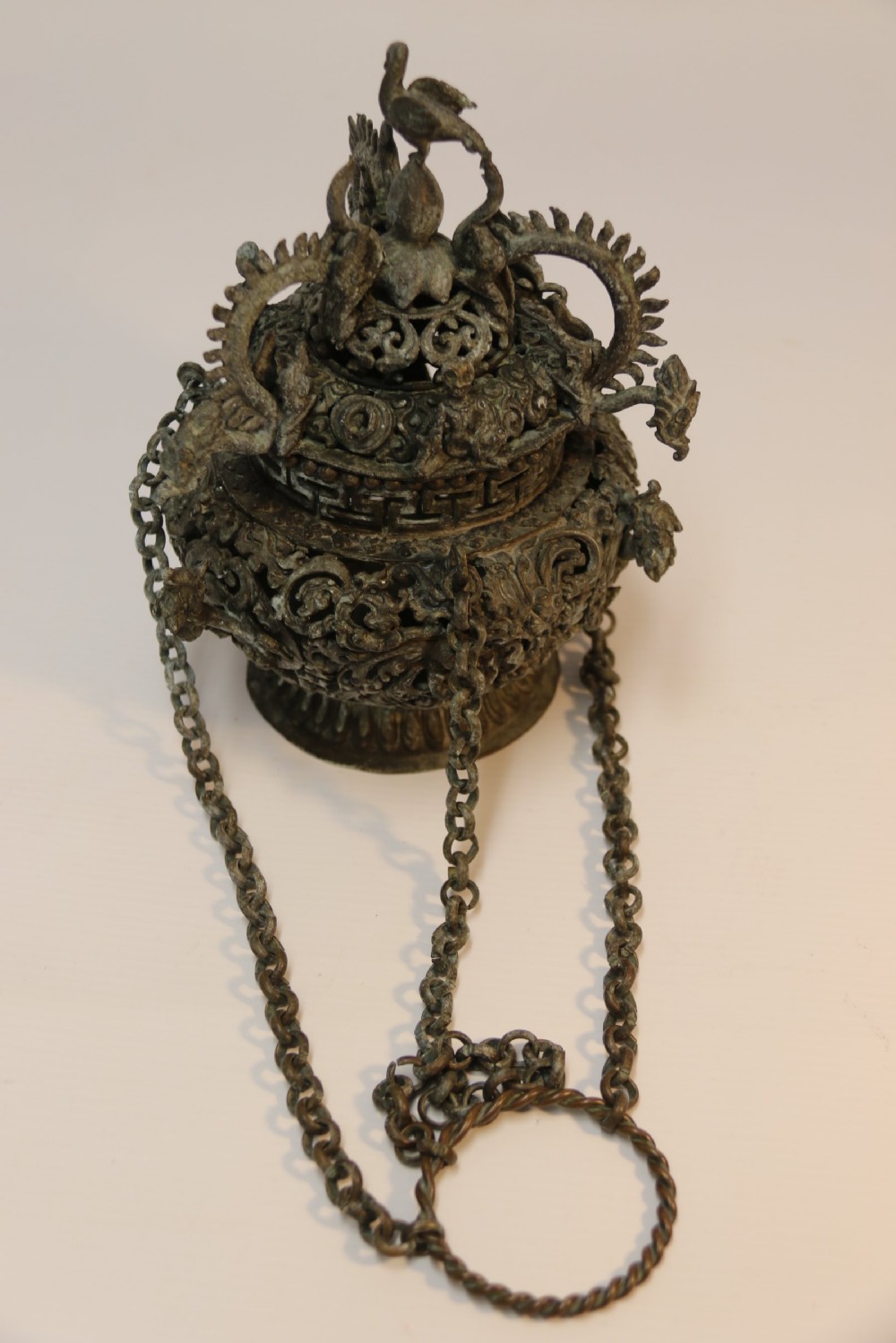 A dark patinated bronze hanging incense burner featuring dragon openwork motifs and a bird finial suspended by three link chains. View XII