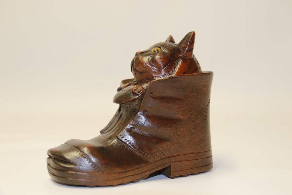 A Black Forest carved walnut kitten sitting in a boot