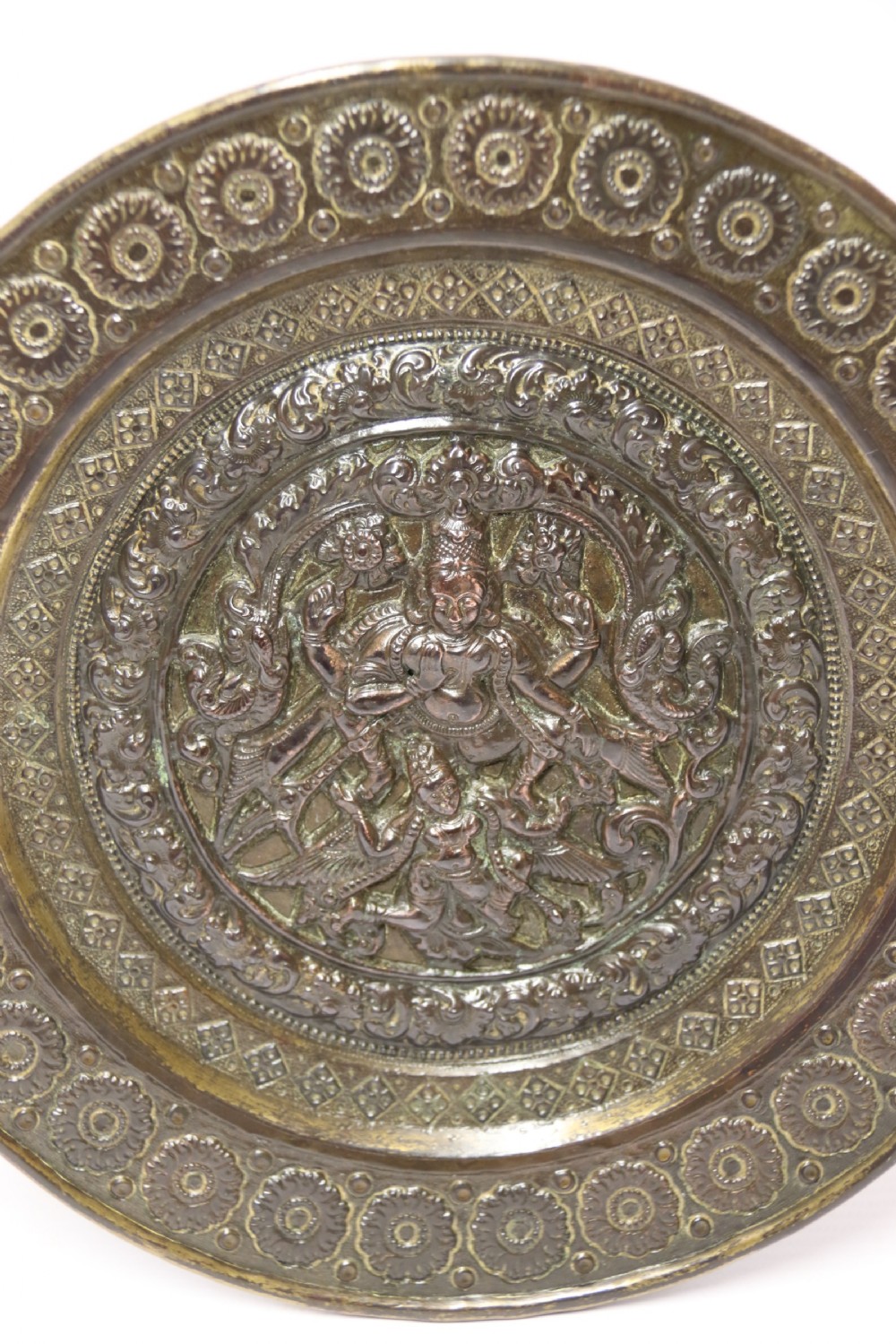 A circular 19th-century Indian bronze plaque featuring intricate chased floral borders and a central high-relief Hindu deity figure. View II
