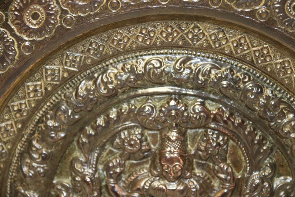 A circular 19th-century Indian bronze plaque featuring intricate chased floral borders and a central high-relief Hindu deity figure. View IV