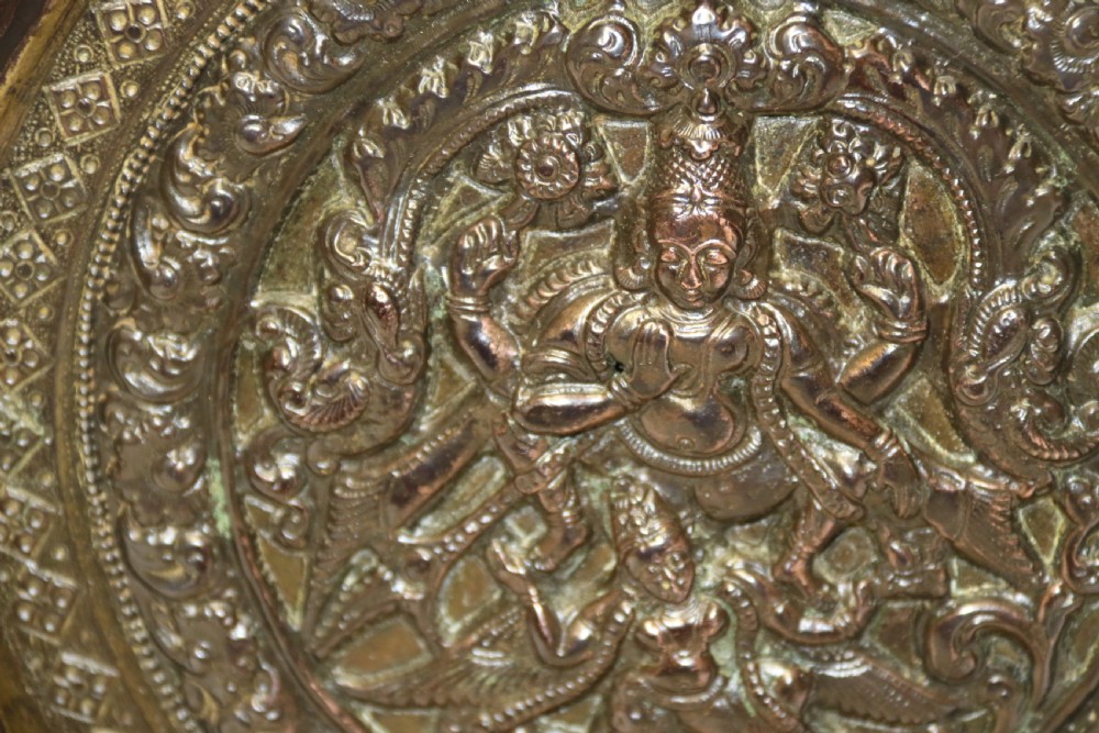 A circular 19th-century Indian bronze plaque featuring intricate chased floral borders and a central high-relief Hindu deity figure. View VI