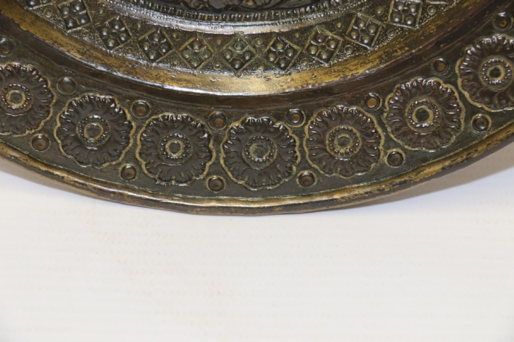A circular 19th-century Indian bronze plaque featuring intricate chased floral borders and a central high-relief Hindu deity figure. View VII