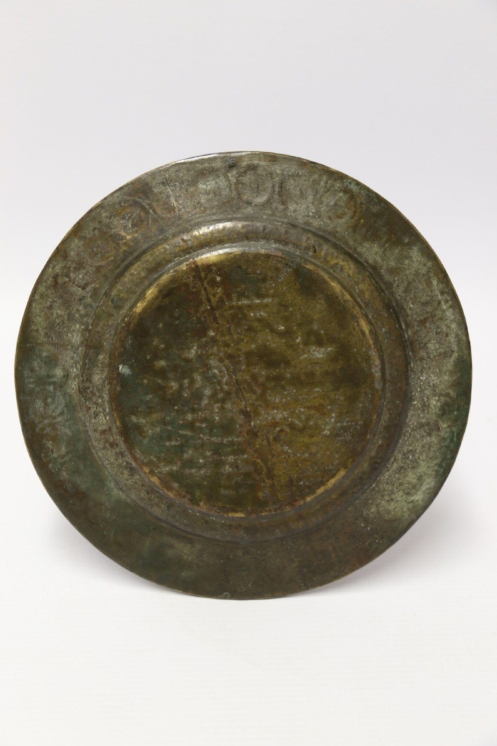 A circular 19th-century Indian bronze plaque featuring intricate chased floral borders and a central high-relief Hindu deity figure. View IX