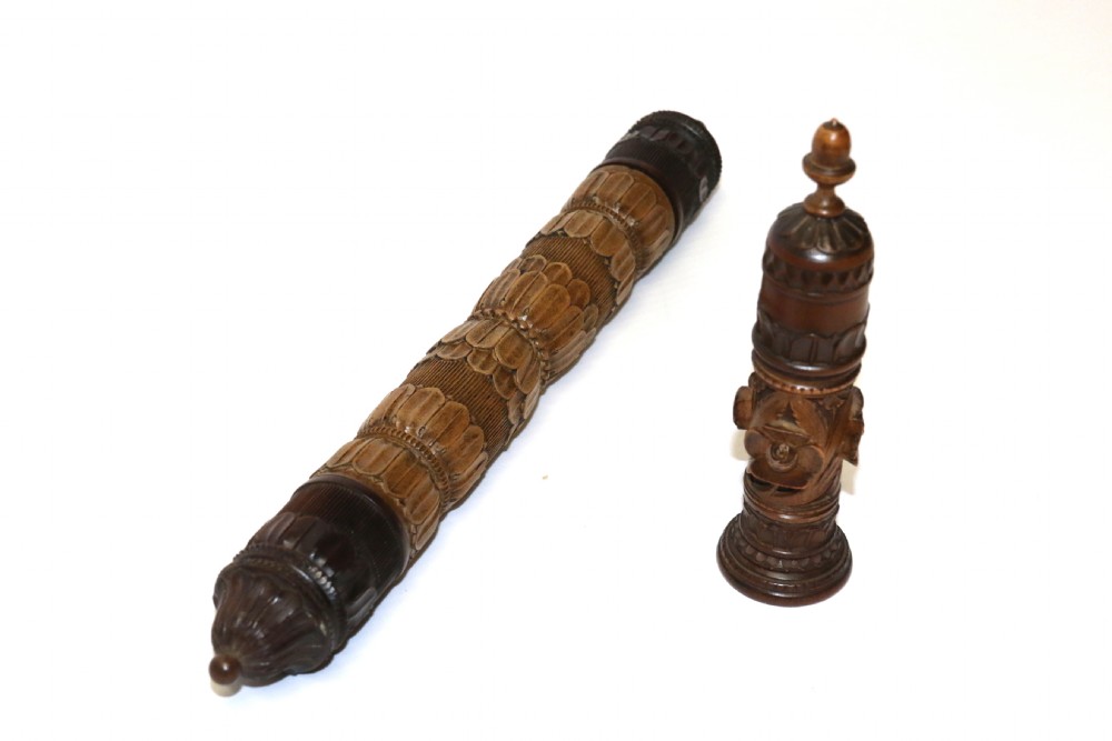 Two hand-carved fruitwood sewing cases featuring cylindrical shapes, leaf relief patterns, and turned finials.