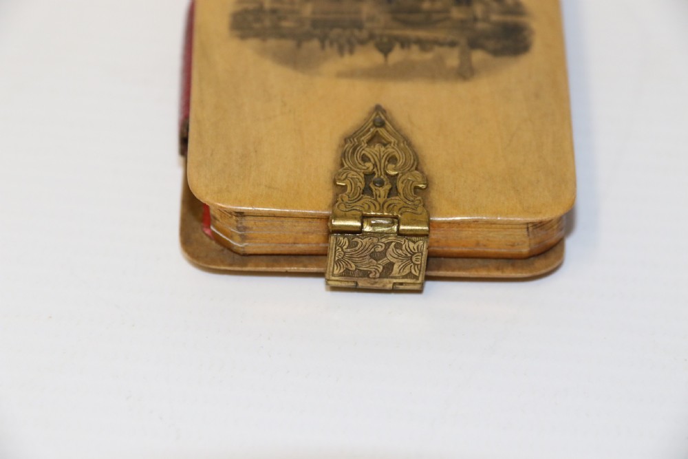 An antique Victorian Mauchline ware wooden pocket notebook displaying a black oval transfer print depicting the Arcades at Crystal Palace, featuring an ornate brass top clasp. View IV