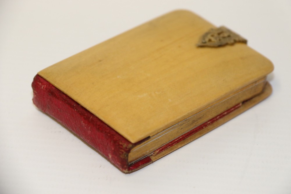 An antique Victorian Mauchline ware wooden pocket notebook displaying a black oval transfer print depicting the Arcades at Crystal Palace, featuring an ornate brass top clasp. View VI