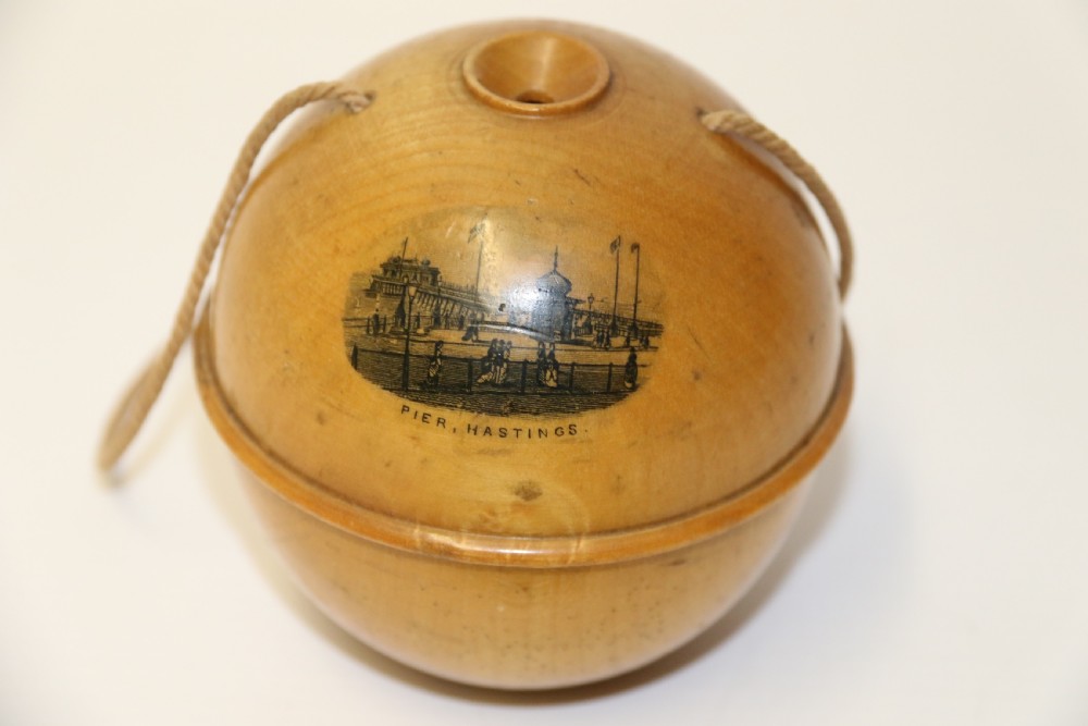 A spherical turned wooden Mauchline ware string holder featuring a black transfer print of Hastings Pier and a hanging cord. View III