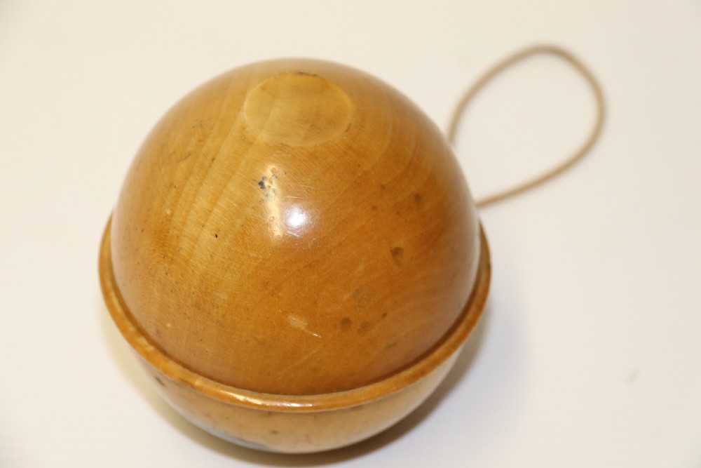 A spherical turned wooden Mauchline ware string holder featuring a black transfer print of Hastings Pier and a hanging cord. View VI