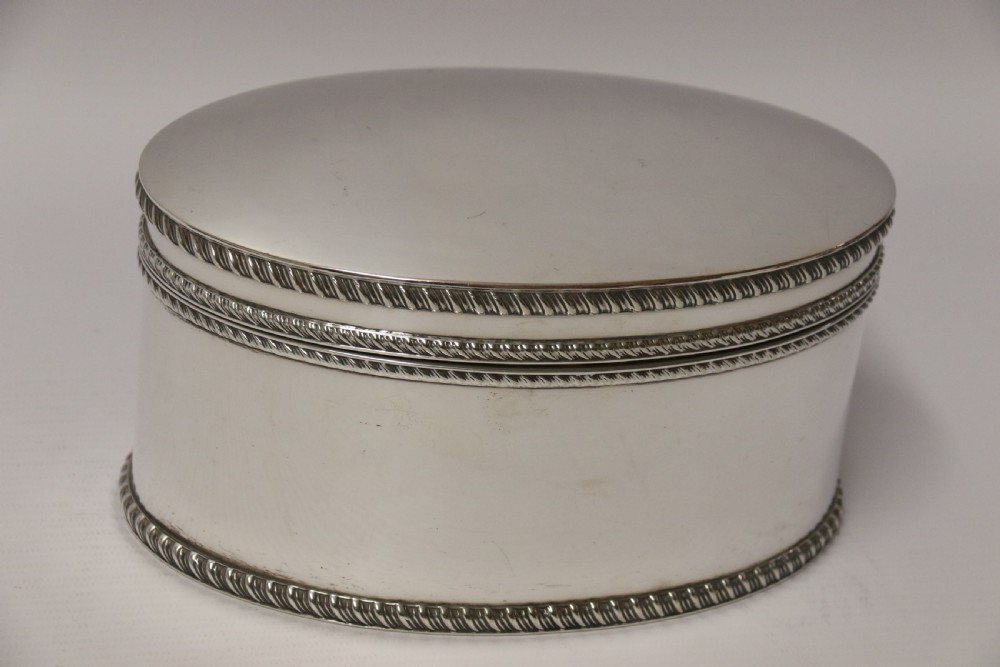 A polished silver-plated oval box featuring a smooth domed lid and rope-twist borders around the rim and base.