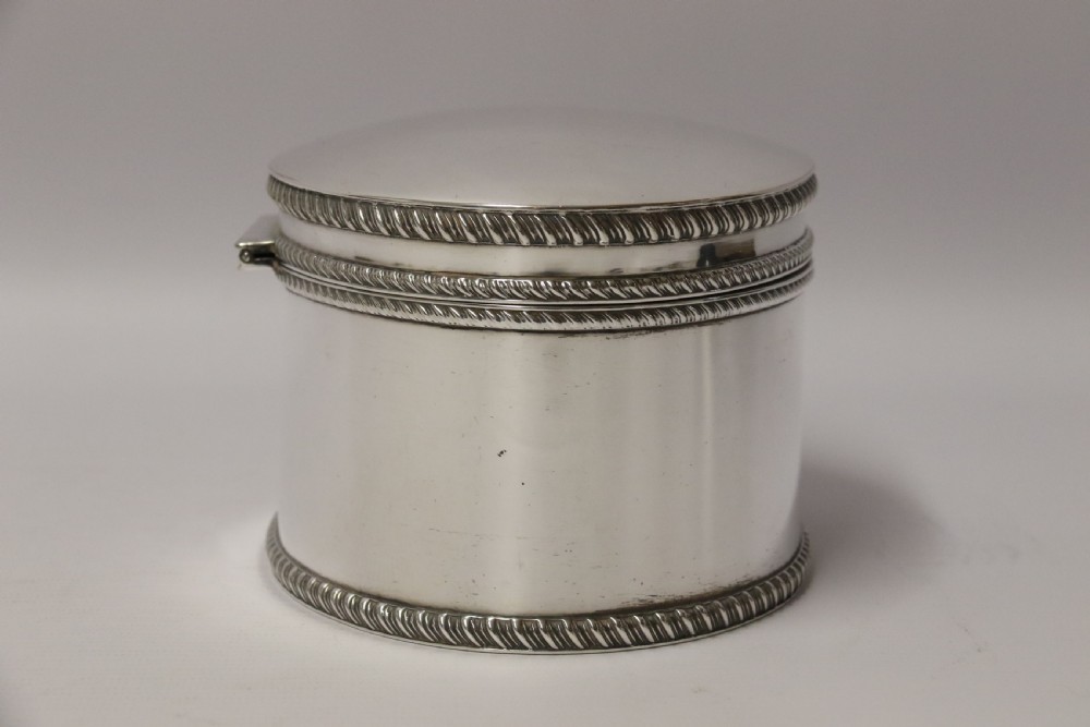 A polished silver-plated oval box featuring a smooth domed lid and rope-twist borders around the rim and base. View V