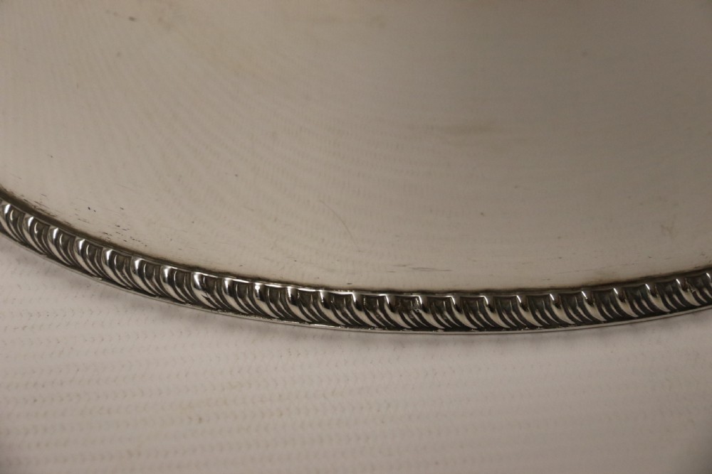 A polished silver-plated oval box featuring a smooth domed lid and rope-twist borders around the rim and base. View IX