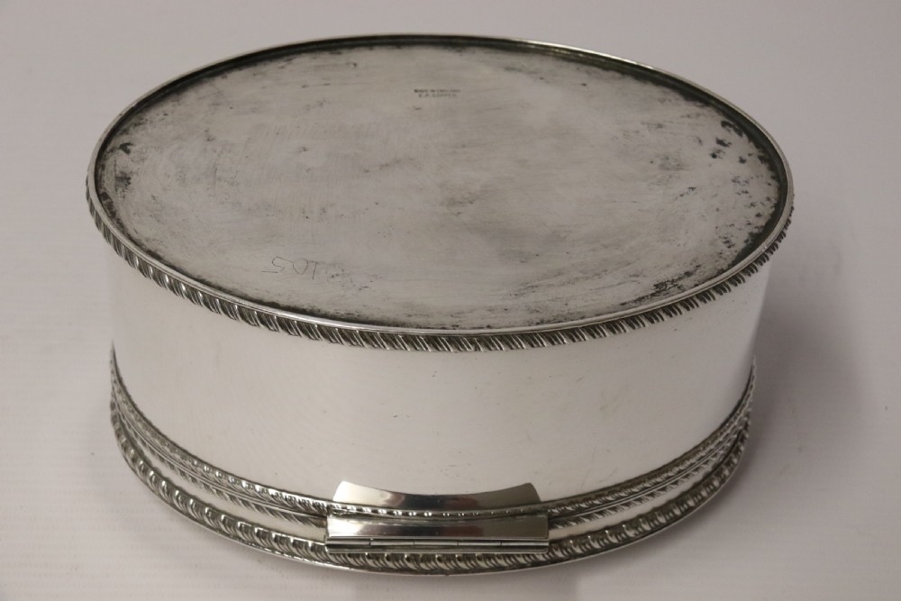 A polished silver-plated oval box featuring a smooth domed lid and rope-twist borders around the rim and base. View XI