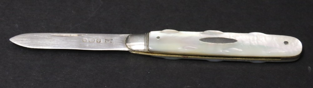 A George V sterling silver folding fruit knife featuring a hallmarked blade and a shaped mother of pearl handle with brass lining.
