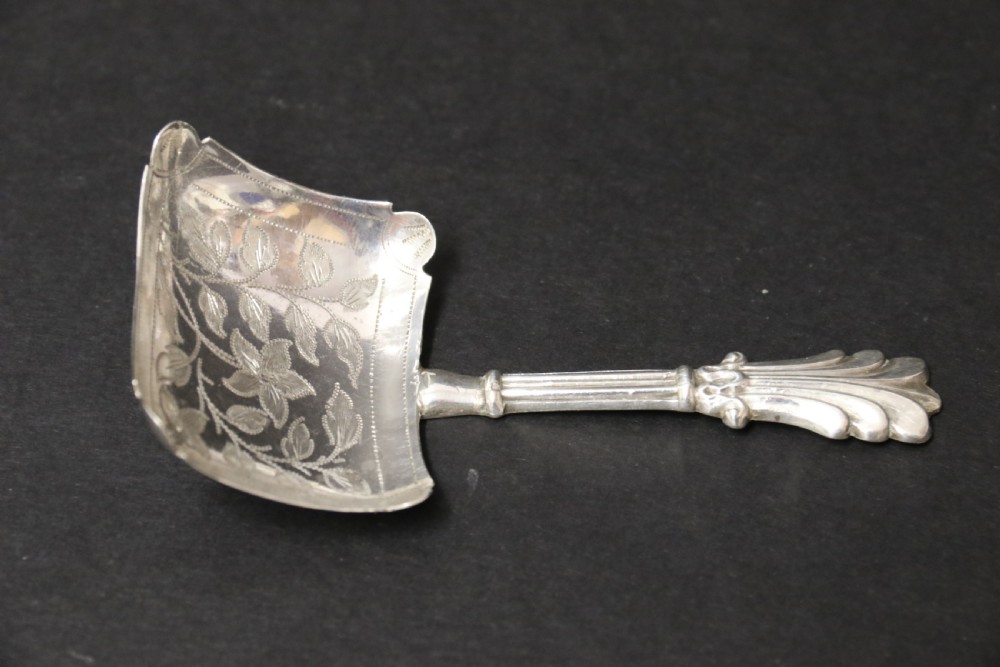 An antique Victorian silver caddy spoon featuring a rectangular bowl with bright-cut floral and leaf engraving and a decorative short handle. View II