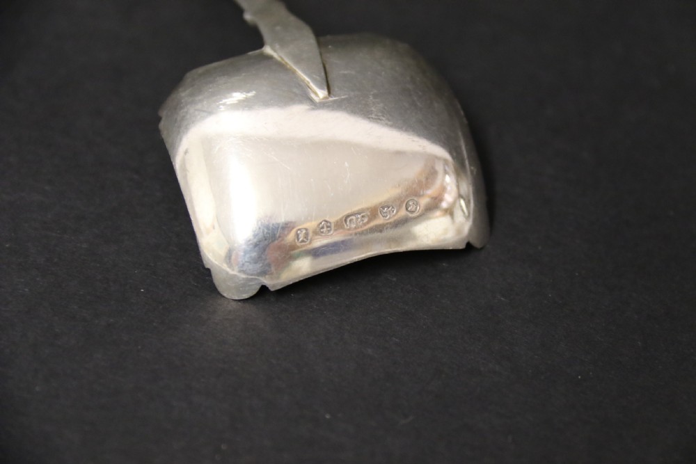 An antique Victorian silver caddy spoon featuring a rectangular bowl with bright-cut floral and leaf engraving and a decorative short handle. View VI