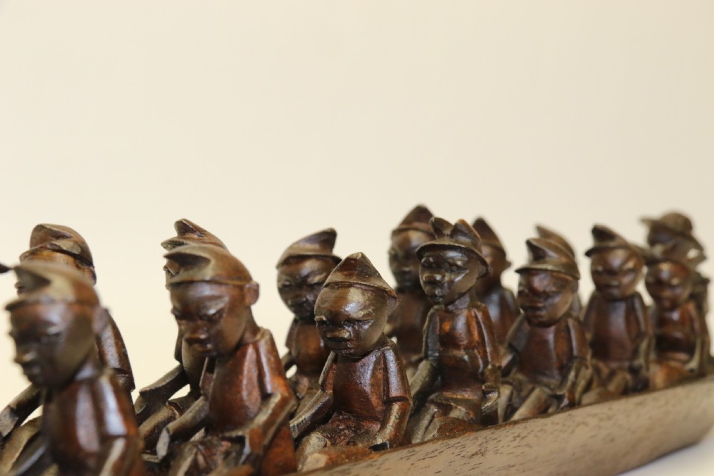 An African Carved Wooden model of a dug-out canoe with 18 seated tribal figures. View VI