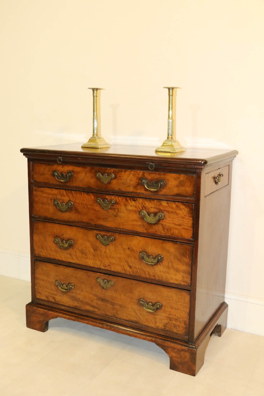 An 18th-century English walnut bachelors writing chest featuring four graduated drawers, brass plate handles, bracket feet, and side carrying handles.