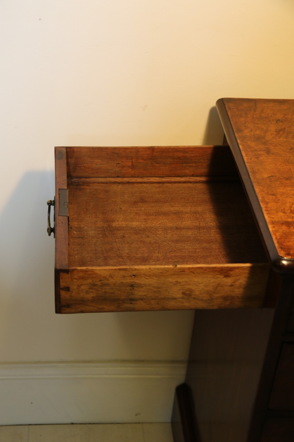 An 18th-century English walnut bachelors writing chest featuring four graduated drawers, brass plate handles, bracket feet, and side carrying handles. View XVIII