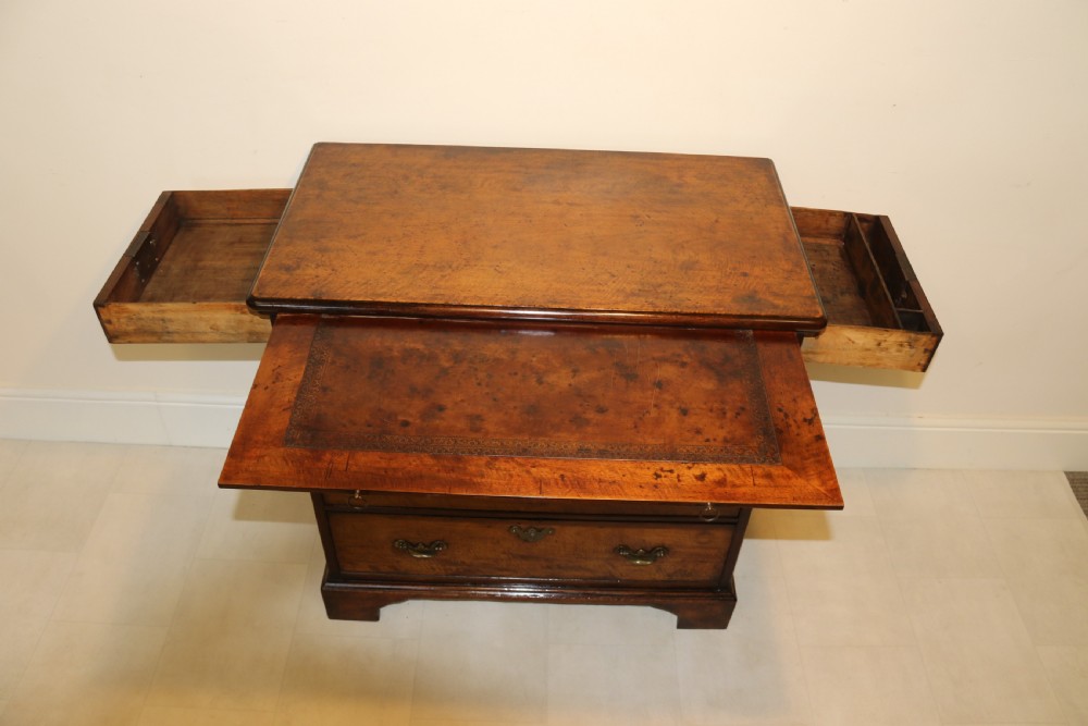 An 18th-century English walnut bachelors writing chest featuring four graduated drawers, brass plate handles, bracket feet, and side carrying handles. View XX