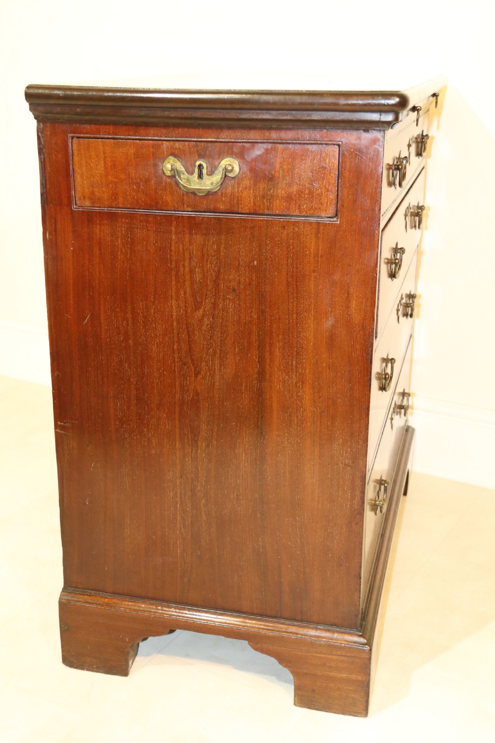An 18th-century English walnut bachelors writing chest featuring four graduated drawers, brass plate handles, bracket feet, and side carrying handles. View XXV