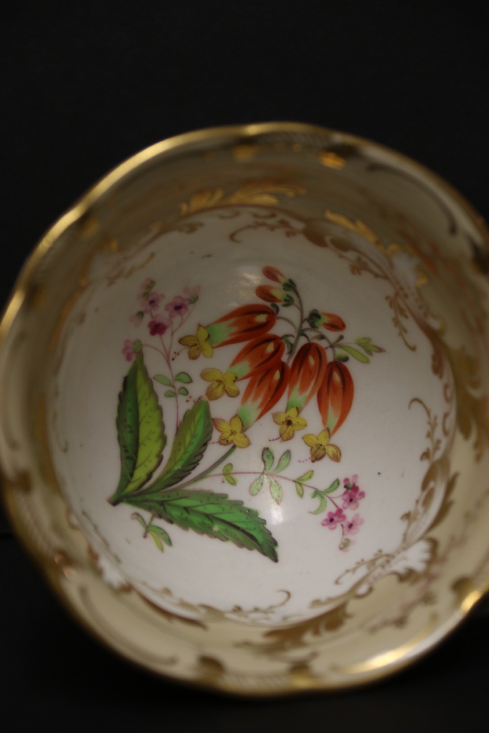 An early nineteenth-century Davenport porcelain cabinet trio comprising a teacup, coffee cup, and matching saucer decorated with hand-painted botanical flowers and gilded scrolling borders. View VI