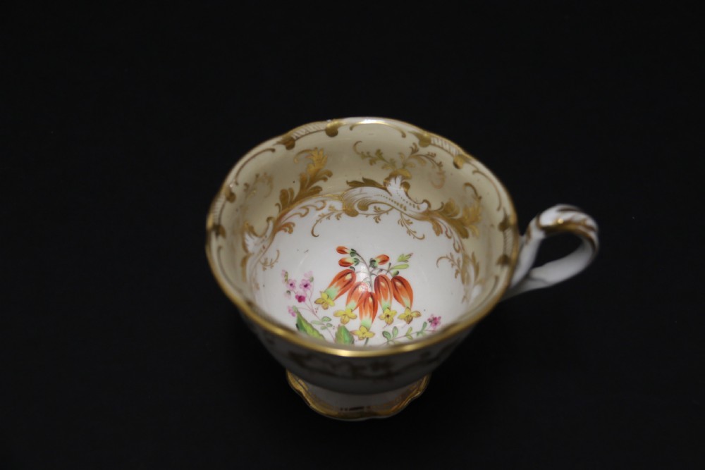 An early nineteenth-century Davenport porcelain cabinet trio comprising a teacup, coffee cup, and matching saucer decorated with hand-painted botanical flowers and gilded scrolling borders. View VII