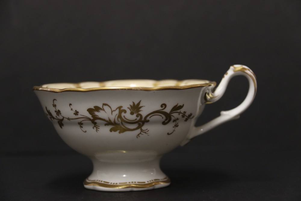 An early nineteenth-century Davenport porcelain cabinet trio comprising a teacup, coffee cup, and matching saucer decorated with hand-painted botanical flowers and gilded scrolling borders. View XII