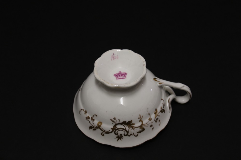 An early nineteenth-century Davenport porcelain cabinet trio comprising a teacup, coffee cup, and matching saucer decorated with hand-painted botanical flowers and gilded scrolling borders. View XIII