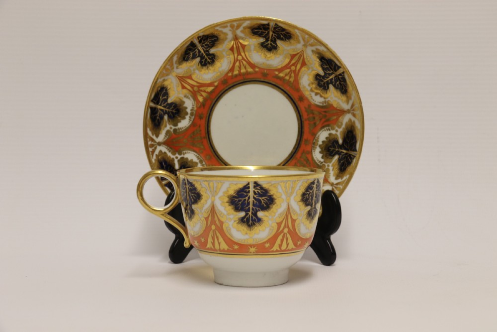 An early nineteenth-century porcelain cabinet cup and matching saucer decorated with orange panels, cobalt blue leaf motifs, and gold gilding. View II