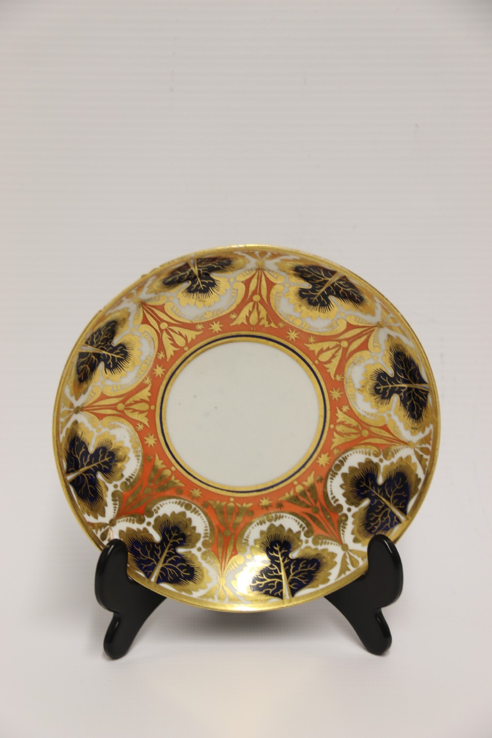 An early nineteenth-century porcelain cabinet cup and matching saucer decorated with orange panels, cobalt blue leaf motifs, and gold gilding. View V