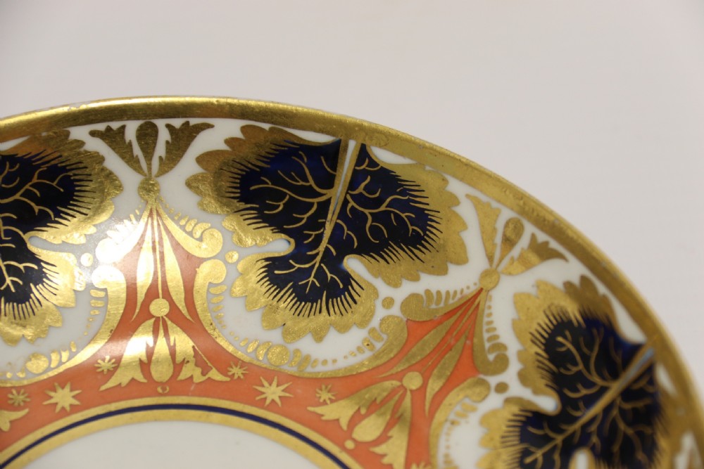 An early nineteenth-century porcelain cabinet cup and matching saucer decorated with orange panels, cobalt blue leaf motifs, and gold gilding. View VI
