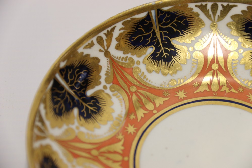 An early nineteenth-century porcelain cabinet cup and matching saucer decorated with orange panels, cobalt blue leaf motifs, and gold gilding. View VII