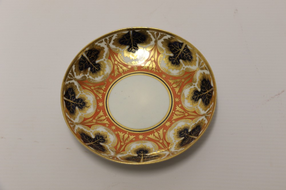 An early nineteenth-century porcelain cabinet cup and matching saucer decorated with orange panels, cobalt blue leaf motifs, and gold gilding. View VIII