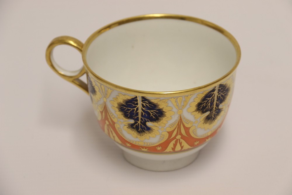 An early nineteenth-century porcelain cabinet cup and matching saucer decorated with orange panels, cobalt blue leaf motifs, and gold gilding. View IX