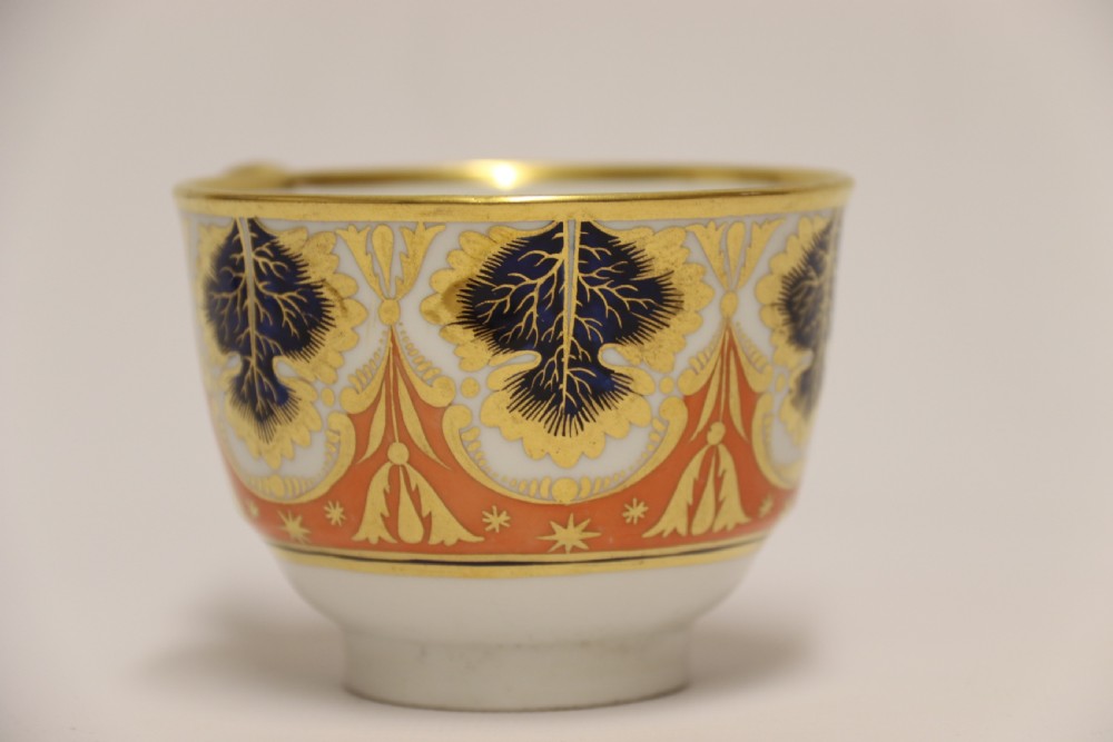 An early nineteenth-century porcelain cabinet cup and matching saucer decorated with orange panels, cobalt blue leaf motifs, and gold gilding. View XI
