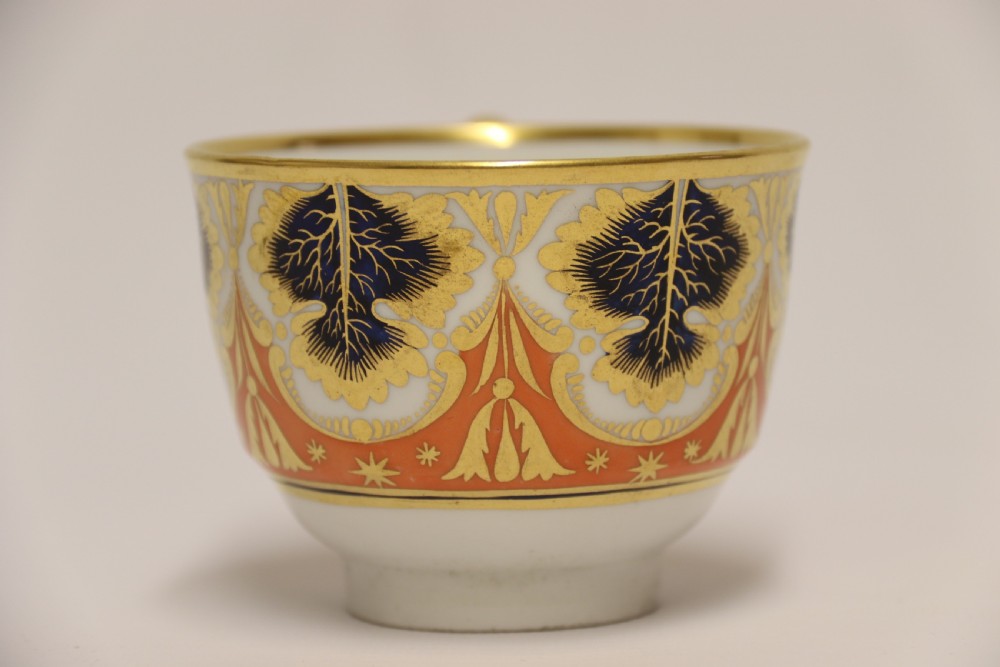 An early nineteenth-century porcelain cabinet cup and matching saucer decorated with orange panels, cobalt blue leaf motifs, and gold gilding. View XII