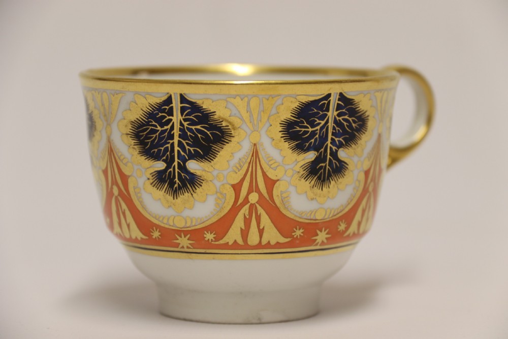 An early nineteenth-century porcelain cabinet cup and matching saucer decorated with orange panels, cobalt blue leaf motifs, and gold gilding. View XIII