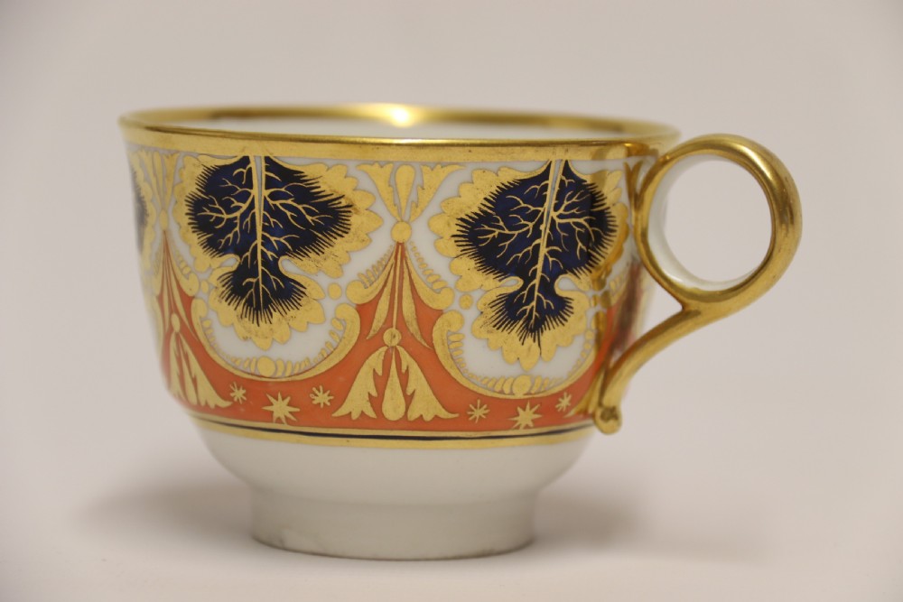 An early nineteenth-century porcelain cabinet cup and matching saucer decorated with orange panels, cobalt blue leaf motifs, and gold gilding. View XIV
