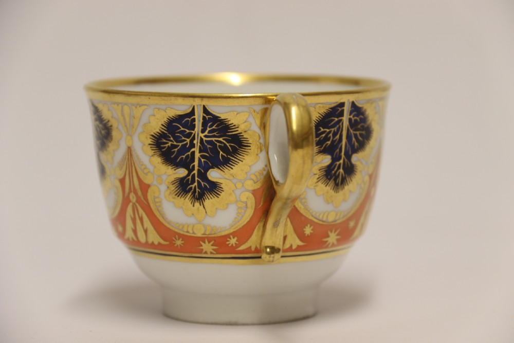An early nineteenth-century porcelain cabinet cup and matching saucer decorated with orange panels, cobalt blue leaf motifs, and gold gilding. View XV