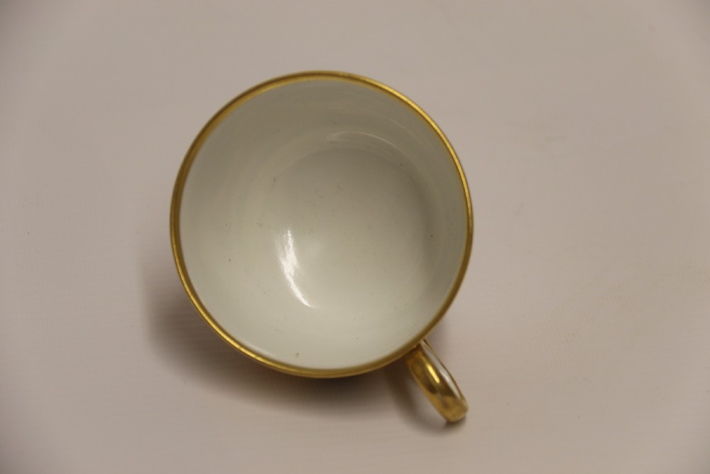 An early nineteenth-century porcelain cabinet cup and matching saucer decorated with orange panels, cobalt blue leaf motifs, and gold gilding. View XVI