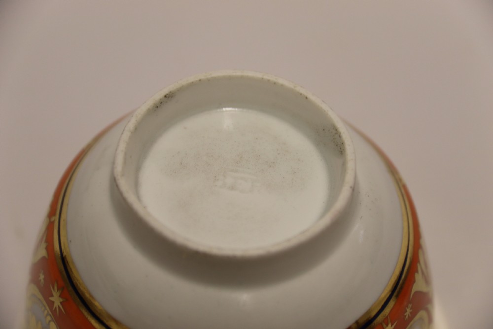An early nineteenth-century porcelain cabinet cup and matching saucer decorated with orange panels, cobalt blue leaf motifs, and gold gilding. View XVIII