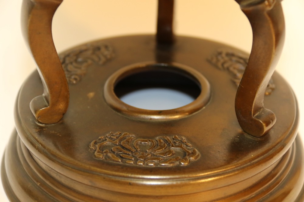 A pair of patinated Japanese Meiji period bronze vases featuring low-relief floral carving, curved scroll handles, and tripod legs resting on circular bases. View VII