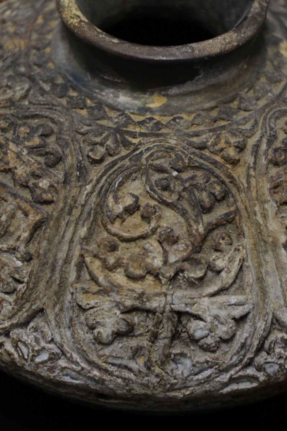 A squat, rounded antique Indian earthenware vase featuring deeply incised floral and arch motifs across its upper body. View VI