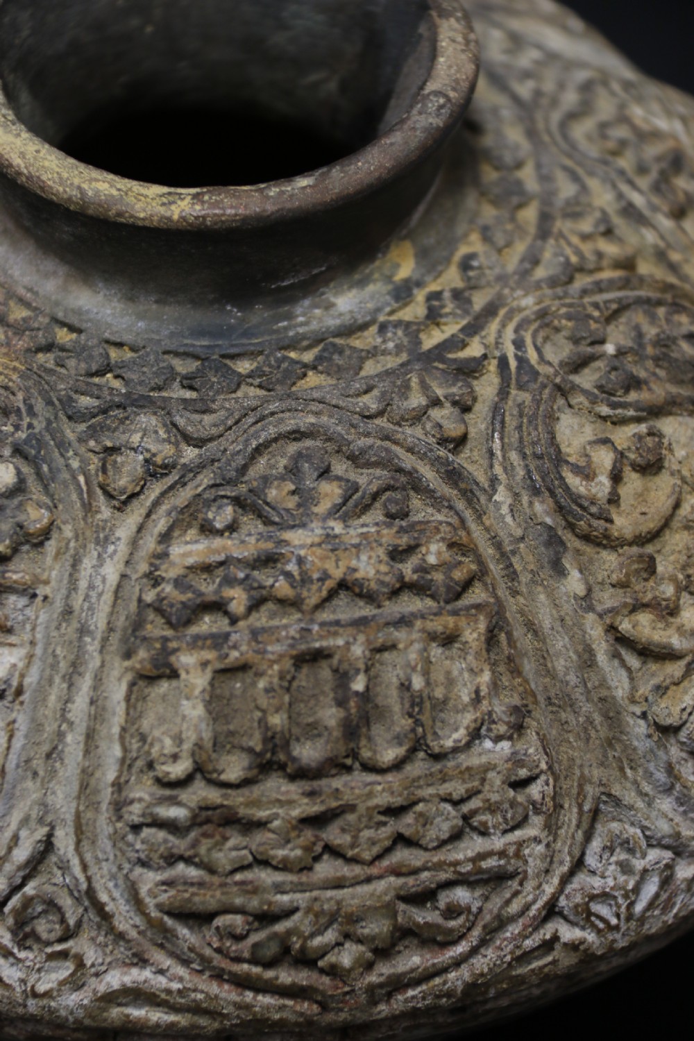 A squat, rounded antique Indian earthenware vase featuring deeply incised floral and arch motifs across its upper body. View VIII