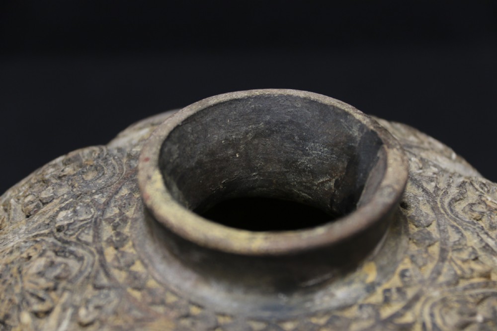 A squat, rounded antique Indian earthenware vase featuring deeply incised floral and arch motifs across its upper body. View IX