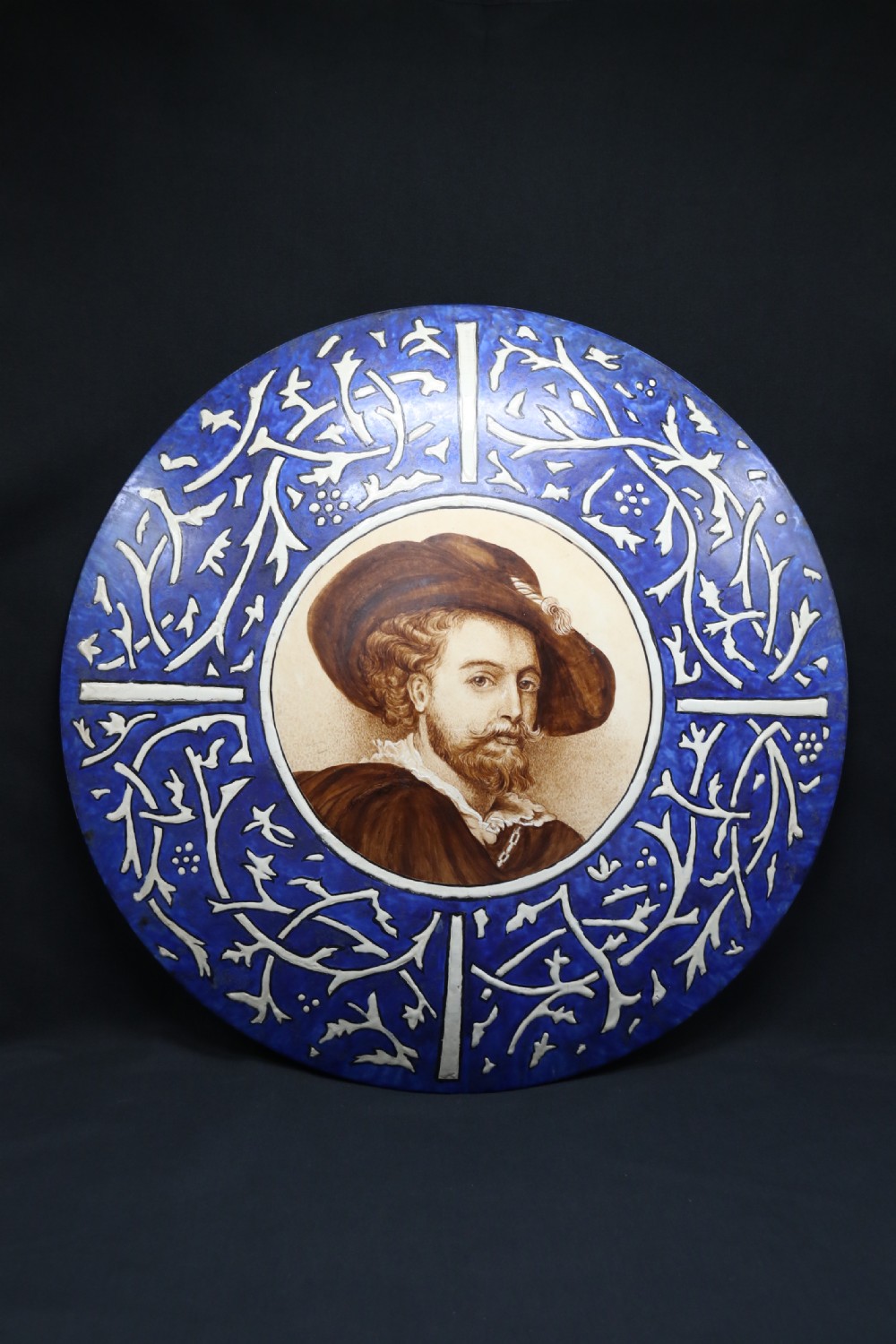 A bold impressive hand painted Continental pottery plaque with a central portrait of Rubens