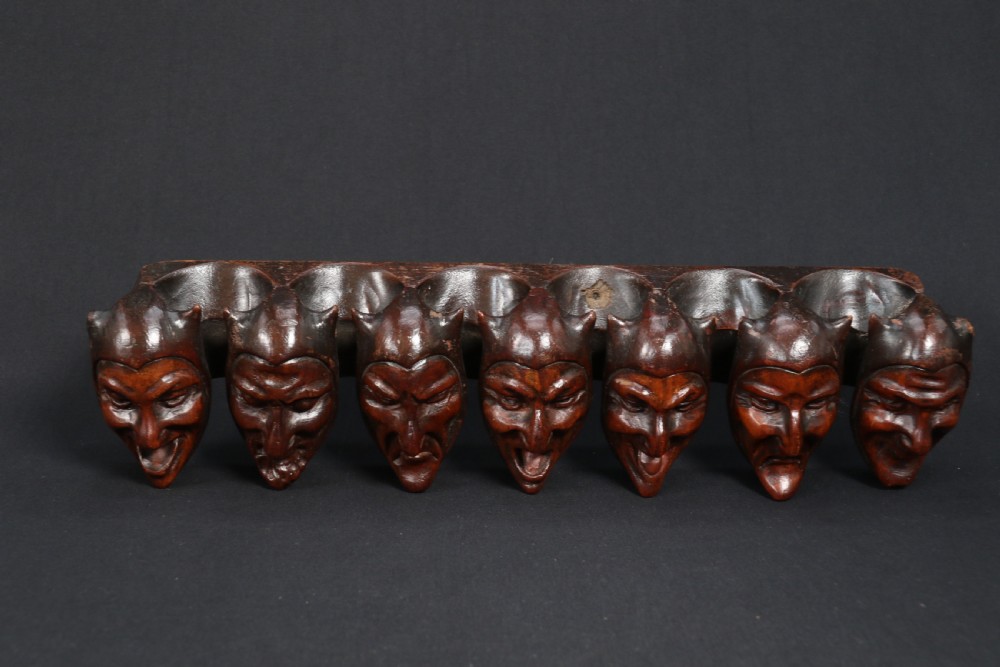 A superb Black Forest spoon rack carved in the devilish faces of the seven deadly sins. View XI