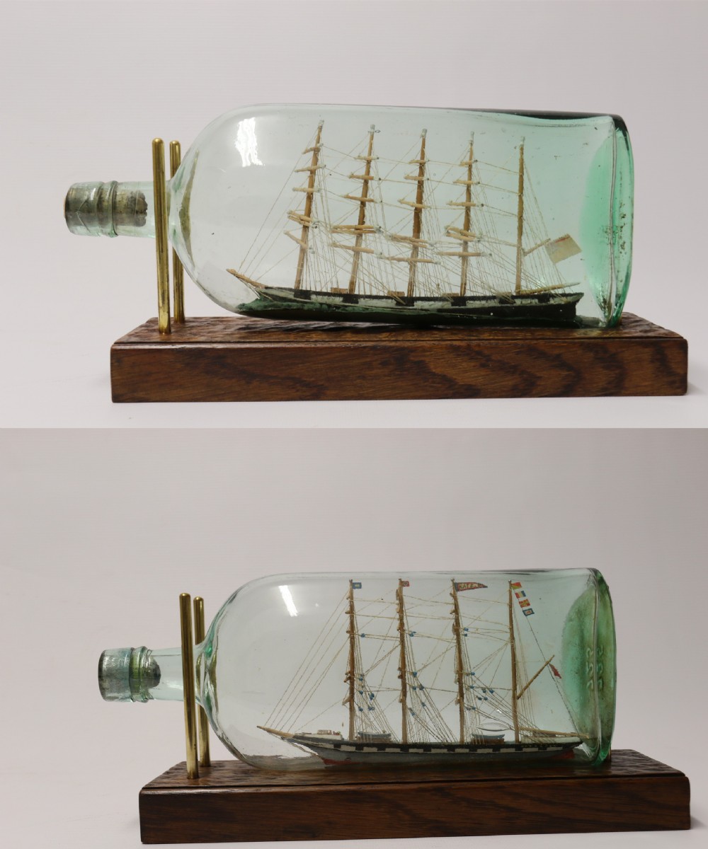 A rare pair of early 20th century model sailing ships in bottles displayed on wooden stands