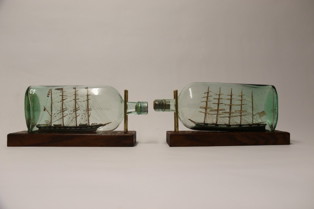 A rare pair of early 20th century model sailing ships in bottles displayed on wooden stands View II